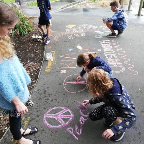 Ungt fólk býr til listaverk úr krít á gangstétt í Christchurch. Fjölskyldur sem taka þátt í uppbyggjandi starfsemi á vegum bahá'í samfélagsins hóf að gera þessi listaverk til þess að vekja von eftir hryðjuverkarárásina þann 15. mars. 